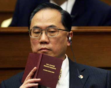 Hong Kong's acting Chief Executive Donald Tsang holds a copy of "Hong Kong Basic Law", the 'mini-constitution' of the territory, during a Legislative Council meeting in Hong Kong April 6, 2005. Tsang said on Wednesday the Hong Kong government will ask China to interpret its constitution to settle a dispute over the term of its next leader, despite fears it will undermine the city's high degree of autonomy.