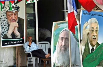 A Palestinian man sits in front of a store decorated with pictures of late Palestinian leader Yasser Arafat, left, late Hamas spiritual leader Sheik Ahmed Yassin, centre, and Palestinian Authority President Mahmoud Abbas, also known as Abu Mazen, right, in Gaza city, Thursday April 14, 2005. The Palestinian militant group Hamas on Thursday accused the ruling Fatah movement of trying to delay an upcoming parliamentary election, and said it was lobbying lawmakers to ensure the vote will be held on time. (AP Photo/Adel Hana) 