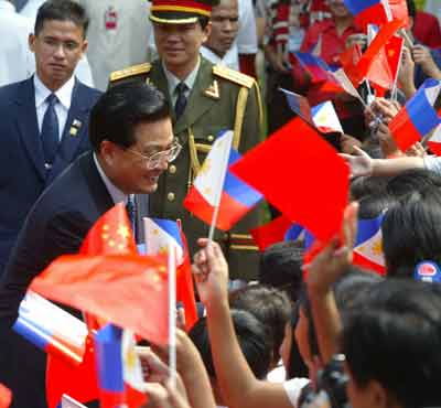 Visiting Chinese President Hu Jintao (2nd L) greets flag-waving Philippine schoolchildren during a welcome ceremony at the presidential palace in Manila April 27, 2005. Hu affirmed burgeoning ties with the Philippines on Wednesday by agreeing investments and loans worth $1.6 billion to fund infrastructure and mining projects in the Southeast Asian nation. [Reuters]