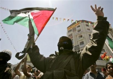 A Palestinian militant from the al-Aqsa Martyrs Brigades flashes a V-sign as other Palestinians wave national flags during a demonstration to mark the 57th anniversary of Al Nakba, or the catastrophe, the Arabic term used to describe the day Israel was created, in the West Bank town of Ramallah, Sunday May 15, 2005. Palestinians in the West Bank and Gaza Strip held rallies in lament of Israel's founding 57 years ago. (AP