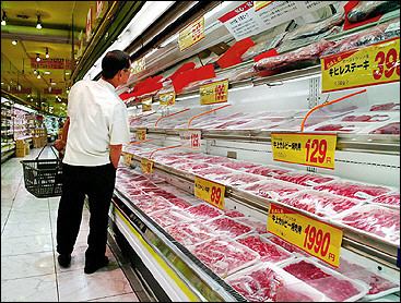 A customer checks packs of beef at a supermarket in Tokyo.