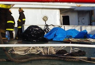 ruguayan firefighters stand by covered bodies on the deck of the Ukranian fishing vessel 'Simeiz' in Montevideo, Uruguay, Thursday, June 23, 2005.