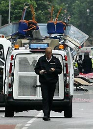 A police officer walks from the bus destroyed by a bomb in London yesterday. Police said they believed at least 33 people had been killed in a series of blasts which rocked central London.