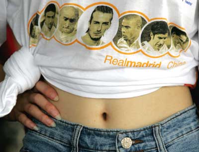 A Chinese girl wearing a T-shirt printed with headshots of Real Madrid players waits at a welcome ceremony at Xianghe town in Hebei Province, eastern Beijing July 20, 2005. Real Madrid starts a four-day tour to China on Wednesday and will face Beijing Guoan in a friendly match at Beijing Workers's Stadium on Saturday.