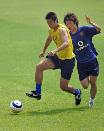 Manchester United's Dong Fangzhuo (L) and Park Ji-sung battle for the ball during a training session in Beijing July 25, 2005. Manchester United starts a four-day visit to China and will face Beijing Guoan in a friendly match at the Beijing Workers' Stadium on Tuesday. [Reuters]