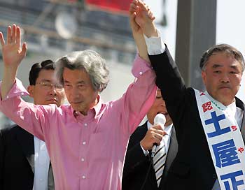 Japanese Prime Minister Junichiro Koizumi (L) raises a hand of Masatada Tsuchiya, a candidate of his ruling Liberal Democratic Party, at Kichijoji railway station in Tokyo at an official launch of a dramatic campaign for a general election August 30, 2005. Koizumi has said the September 11 election is a referendum on reform. REUTERS
