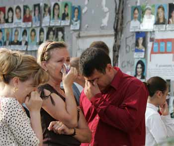 Relatives grieve at Beslan school No.1 in front of a wall with portraits of the victims of the school siege during a commemoration ceremony, September 1, 2005. The sound of wailing cut through the air as bereaved relatives marked the first anniversary of the start of the hostage siege that ended two days later in the deaths of 331 people. [Reuters]