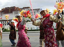 Tibetan children in traditional costume wave flowers at a gathering to celebrate the 40th anniversary of the Tibet Autonomous Region in Lhasa yesterday. 	 Xinhua