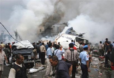 Residents and security officers gather near the wreckage of a jetliner which crashed in Medan, North Sumatra, Indonesia, Monday, Sept. 5, 2005.