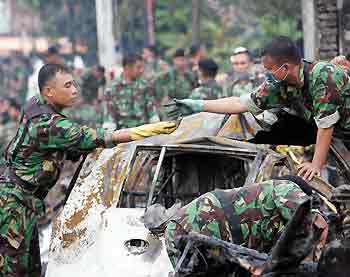 Indonesian soldiers recover human remains and fragments from a car which was destroyed when a plane crashed into a residential area in Medan September 6, 2005.