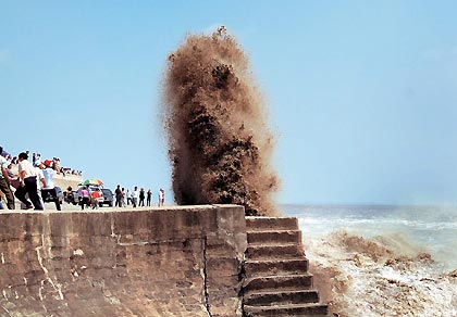 Chinese tourists watch the tide on the bank of Qiantang River in Hangzhou September 7, 2005. Tides waves are seen each year during the eighth month of the lunar calendar, with the most violent tide reaching a height of nine metres.
