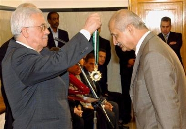 Palestinian Authority President Mahmoud Abbas, also known as Abu Mazen, left, presents his security advisor Moussa Arafat, right, with a medal at his office in Gaza City, in this Tuesday April, 26, 2005, file photo.