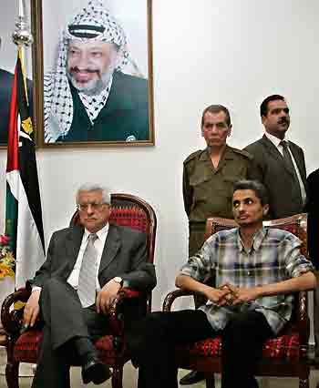 Malnha (R), son of slain ex-security chief Moussa Arafat, sits next to Palestinian president Mahmoud Abbas after he was released in Gaza City September 9, 2005. Palestinian militants said they freed the son of slain ex-security chief Moussa Arafat on Thursday after kidnapping him and shooting dead his father in a raid they called a reprisal for "collaboration" with Israel. [Reuters]