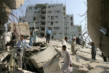 Rescue workers and police officers gather around the collapsed 19-story housing complex after a severe earthquake in Islamabad, Pakistan, Saturday, Oct 8, 2005.