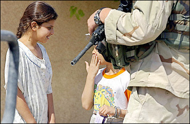 Iraqi girls talk to each other as a US soldier from A/1/112 company infantries patrols a street in the city of Tikrit, north of Baghdad. 
