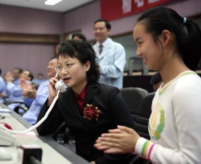 Nie Jielin talks with her husband astronaut Nie Haisheng through a phone at the Beijing Aerospace Command and Control Center Wednesday October 12, 2005. Nie and Fu Junlong are orbiting the Earth in China's second manned spacecraft Shenzhou VI which was launched Wednesday morning. [Xinhua]