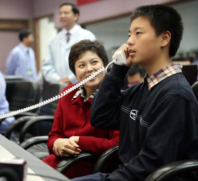 Fei Di talks with his father astronaut Fei Junlong through a phone at the Beijing Aerospace Command and Control Center Wednesday October 12, 2005. Fei and Nie Haisheng are orbiting the Earth in China's second manned spacecraft Shenzhou VI which was launched Wednesday morning. [Xinhua]