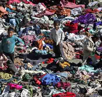 Kashmiri children quake survivors stand on a pile of donated clothes in Tanghdar, 180 km (112 miles) north of Srinagar October 22, 2005. [Reuters]