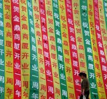 A Chinese woman walks past an advertisement banner for a shopping centre in Liaocheng, east China's Shandong province in this picture taken on October 4, 2005.