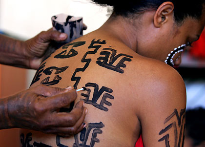 Miss Traditional contestant Shirley O'Connor from the Central Highlands Province waits as her body was being painted with traditional designs by a relative before performing in the contest held in the Papua New Guinea capital city of Port Moresby October 29, 2005. The competition, which raised funds for a local charity, involves contestants wearing their Province's traditional attire, including tattoo designs, and a performance involving dancing and singing which concludes with a speech explaining these traditional acts.