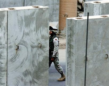 A US soldier walks among concrete walls in Baghdad, Iraq, Tuesday, Nov. 8, 2005.