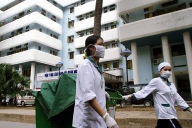 Vietnamese health workers walk past the National Institute for Clinical Research in Tropical Medicine, a hospice for infected bird flu patients, in Hanoi, Vietnam November 11, 2005.