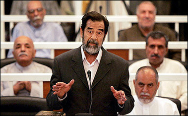 Saddam Hussein speaks to presiding judge Rizgur Ameen Hana Al-Saedi as his trial begins in a heavily fortified courthouse in Baghdad's Green Zone.