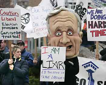 A protestor looks out from the mouth of giant effigy of Canadian Prime Minister Paul Martin during a demonstration in Kelowna, British Columbia November 24, 2005. About 50 Correctional Officers on strike protested outside the site where Martin and the provincial premiers were meeting with native leaders on Thursday. 