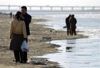 Residents stand on the bank of Songhua River in Harbin, northeast China's Heilongjiang province, November 25, 2005.