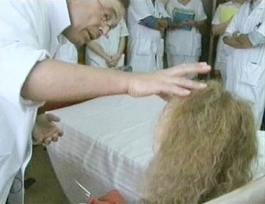 An unidentified woman, bottom, right, is examined by a surgeon, who confers with other hospital staff, part seen, in his image from video released by the Amiens hospital in France, Friday, Dec. 2, 2005. Doctors at the Amiens hospital on Friday, Dec. 2, 2005, said the woman was the recipient on Sunday, Nov. 27, 2005, of the world's first partial face transplant. The 38-year-old woman, whose identity has not been disclosed, was mauled by a dog in May, leaving her with severe facial injuries that her doctors said made it difficult for her to speak and eat. The donor was a brain dead woman. (AP