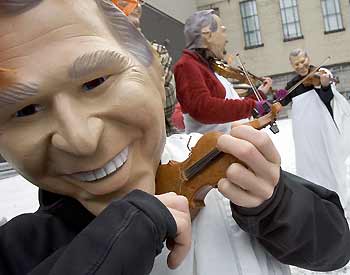 Demonstrators from the Environmental group Energy Action wearing masks depicting U.S. president George Bush fiddle outside the United Nations Climate Change Conference in Montreal December 5, 2005. The group depicted Bush as Emperor Nero fiddling while the planet burned. The group called on the U.S. to rejoin the Kyoto Protocol and said that the country's administration was out-of-touch with its citizens.[Reuters]