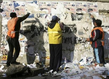 Iraqi workers remove election posters from a wall in central Baghdad December 20, 2005.