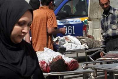 An Iraqi woman walks past the bodies of Iraqis killed during sectarian violence, at a hospital in Baghdad, Iraq, Tuesday, March 14, 2006. [AP]