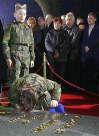 Serb girl Jelena Tmusic wears a Serbian uniform as she kisses the grave of former Serbian leader Slobodan Milosevic during the funeral in his hometown of Pozarevac, some 50 kilometers (30 miles) southeast of Belgrade, Saturday, March 18, 2006. [AP]