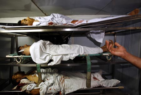 A man prays next to three out of a total of four dead Palestinians in the morgue of the hospital in the West Bank town of Ramallah, May 24, 2006. Israeli troops killed four Palestinians and wounded at least 50 others on Wednesday in clashes that erupted during a rare daylight raid on the occupied West Bank's main city, witnesses and medics said. 
