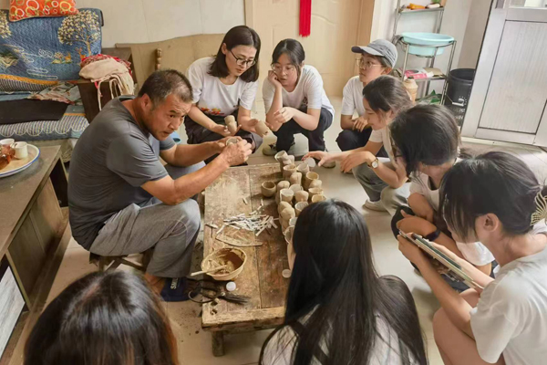 张凯为齐鲁师范学院的学生讲解泥塑制作过程（摄影 楚国帅）.jpg