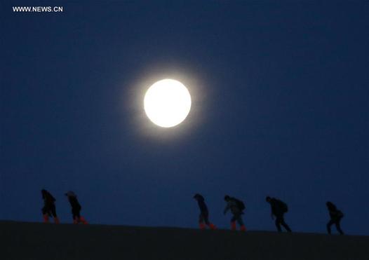 Full moon hikes up Mingsha Mountain in NW China
