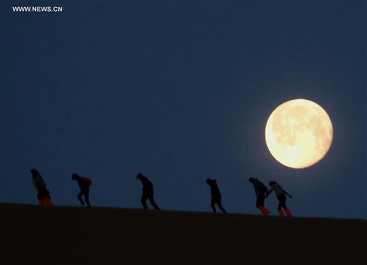 Full moon hikes up Mingsha Mountain in NW China