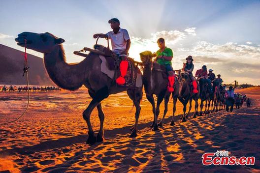 Tourists visit Mingsha Mountain in Dunhuang