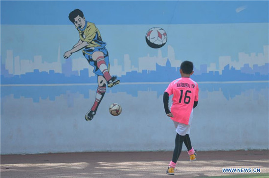 Pupils take part in football training in elementary school in Qingdao