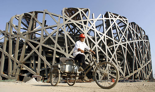 A worker cycles pass the site of the National Stadium, dubbed the 