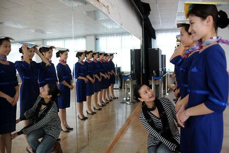 An instructor talks to prospective Olympic award presenters in front of a big mirror during an etiquette training class in Qingdao, the eastern Chinese host city for the sailing competitions during the Olympic Games, March 24, 2008. Some 110 people, most between the ages of 16 to 18, were selected after grueling physical training to be ushers and presenters for the sailing events. [Xinhua]