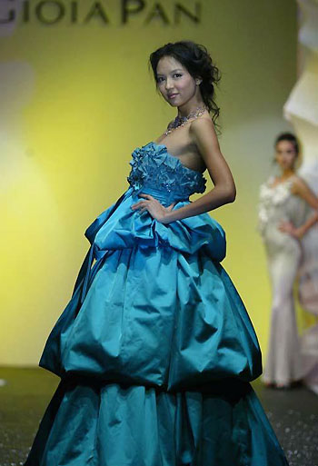 Zhang Zilin, who was crowned Miss World 2007, presents a creation by Taiwan designer Pan Yiliang in Beijing March 31, 2008. Zhang recently finished recording an Olympic song called 'The world follows me'. [Qianlong.com]
