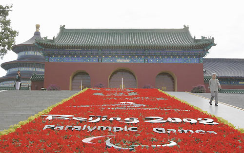 A visitor walks past a floral display with a logo of the Beijing 2008 Paralympic Games at the Temple of Heaven in Beijing, August 31, 2008. [Agencies]