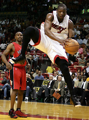 Miami Heat guard Dwyane Wade (R) rebounds the ball against Toronto Raptors guard Mike James during NBA action in Miami, Florida, February 27, 2006. [Reuters]