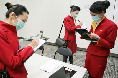 Cathay Pacific flight attendants fill out health declaration forms after disembarking their aircraft during a simulation exercise held at the Hong Kong International Airport March 17, 2006. The scenario simulates a highly contagious disease, such as SARS or avian influenza, infecting a passenger on board a flight arriving in Hong Kong. REUTERS/Alex Hofford/Pool