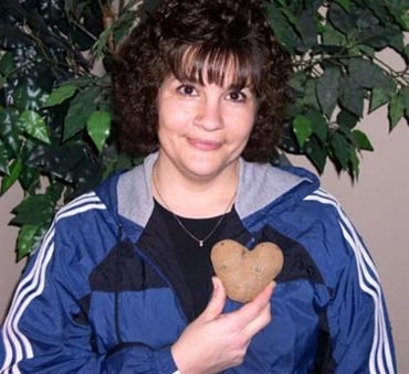In this March 2006 photo taken in Moon Township, Pa., provided by the Idaho Potato Commission, and taken by the family of Linda Greene, Linda Greene is shown holding a heart-shaped potato. The president of the Idaho Potato Commission says there's no way a heart-shaped potato should have made it through the state's inspection system without being pulled aside and turned into french fries. And yet, it did _ during Potato Lover's Month. Greene discovered the potato in February 2006 but only recently alerted the Idaho Potato Commission to the Valentine-shaped tuber. She is storing the potato in a cupboard in her basement. (AP Photo