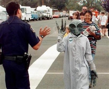 A UFO convention attendee dressed as an alien waves at a Police Officer in Roswell, New Mexico in this undated file photo. A German lawyer hopes to drum up more business by pursuing state compensation claims for people who believe they were abducted by aliens.