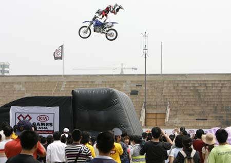 Spectators watch as Chucky Norris of Australia jumps with his motorcycle during a demonstration performance on the opening day of Asia Extreme Games in Shanghai May 3, 2007.