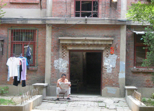 A Chinese man reads newspaper in Juixiaqiao Sub-district in Beijing, June 9, 2007. Local government in Jiuxianqiao and the real estate developer jointly organize the vote on Saturday to see if majority residents of over 5000 families accept the new compensation policy after failed attempts to reach an agreement through other ways. Both notary officials and supervisors are invited to monitor the vote that runs from 9 a.m. to 9 p.m. at six ballot booths. [Sun Yuqing/www.chinadaily.com.cn]